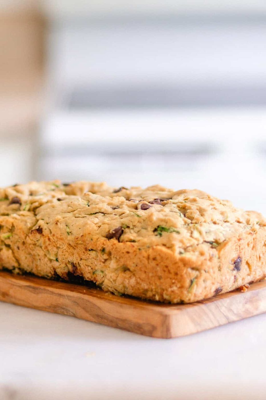 A loaf of gluten-free zucchini bread on a wooden board.