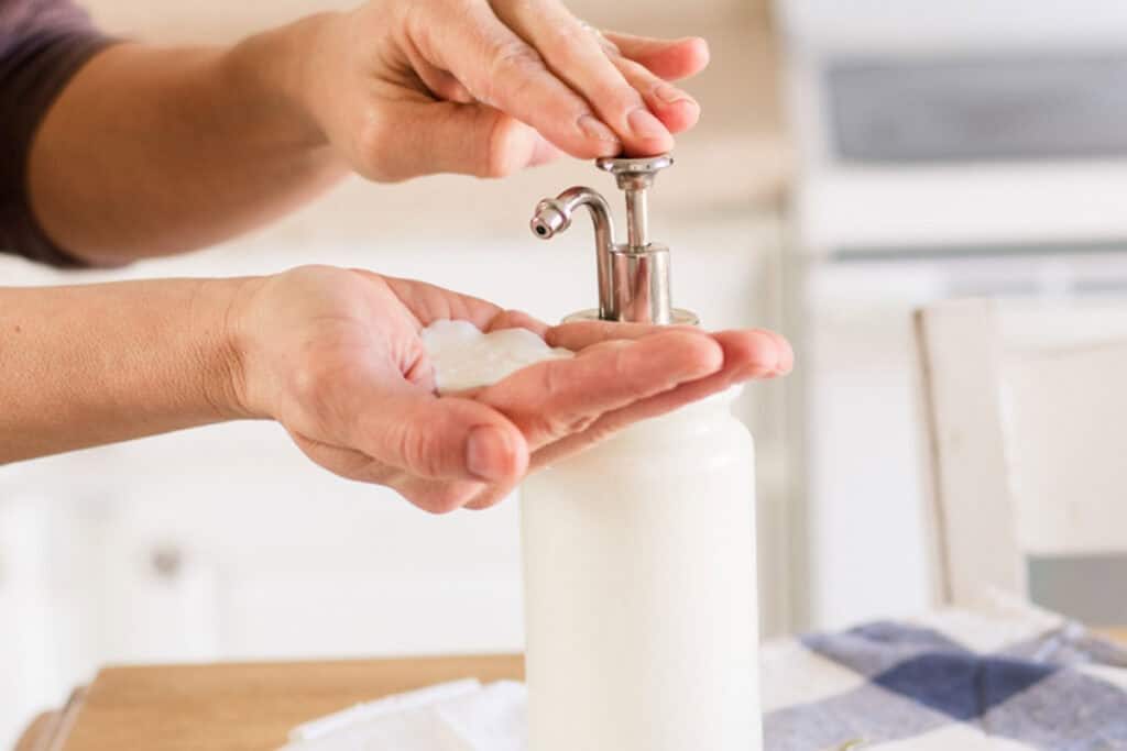 Pumping homemade goat milk lotion into the palm of a hand.
