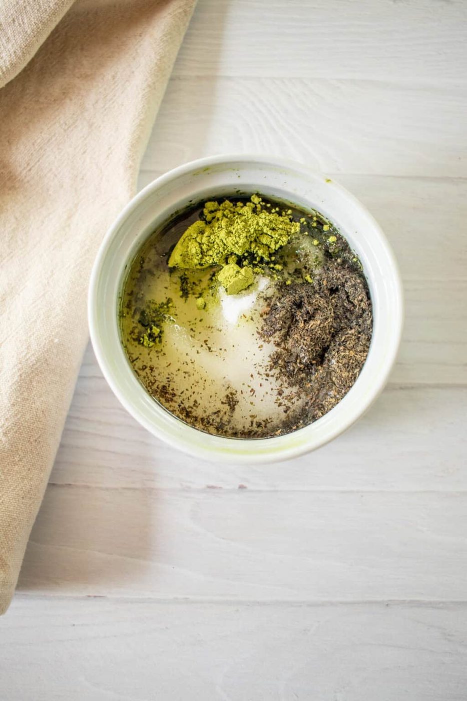 Matcha scrub ingredients in a bowl with liquid.