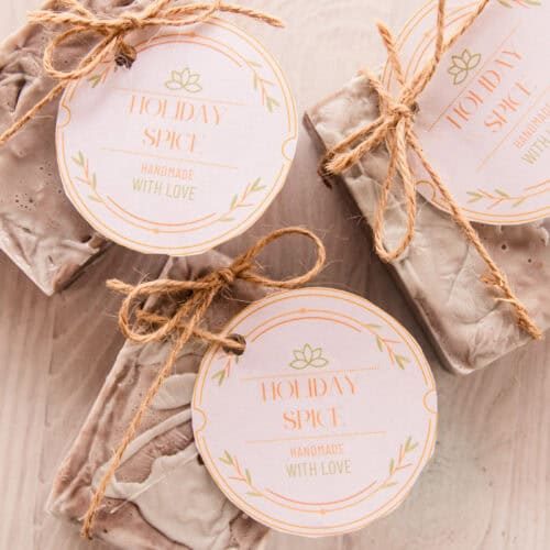 Holiday spice soap with handmade labels tied to them with hemp string on a wooden tabletop.