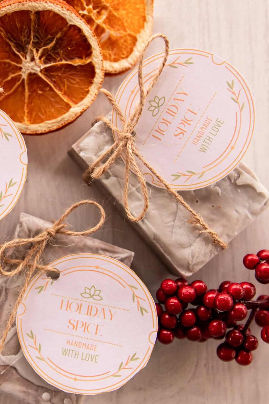 Holiday spice soap bars with holiday gift tags, red berries, and dried oranges.