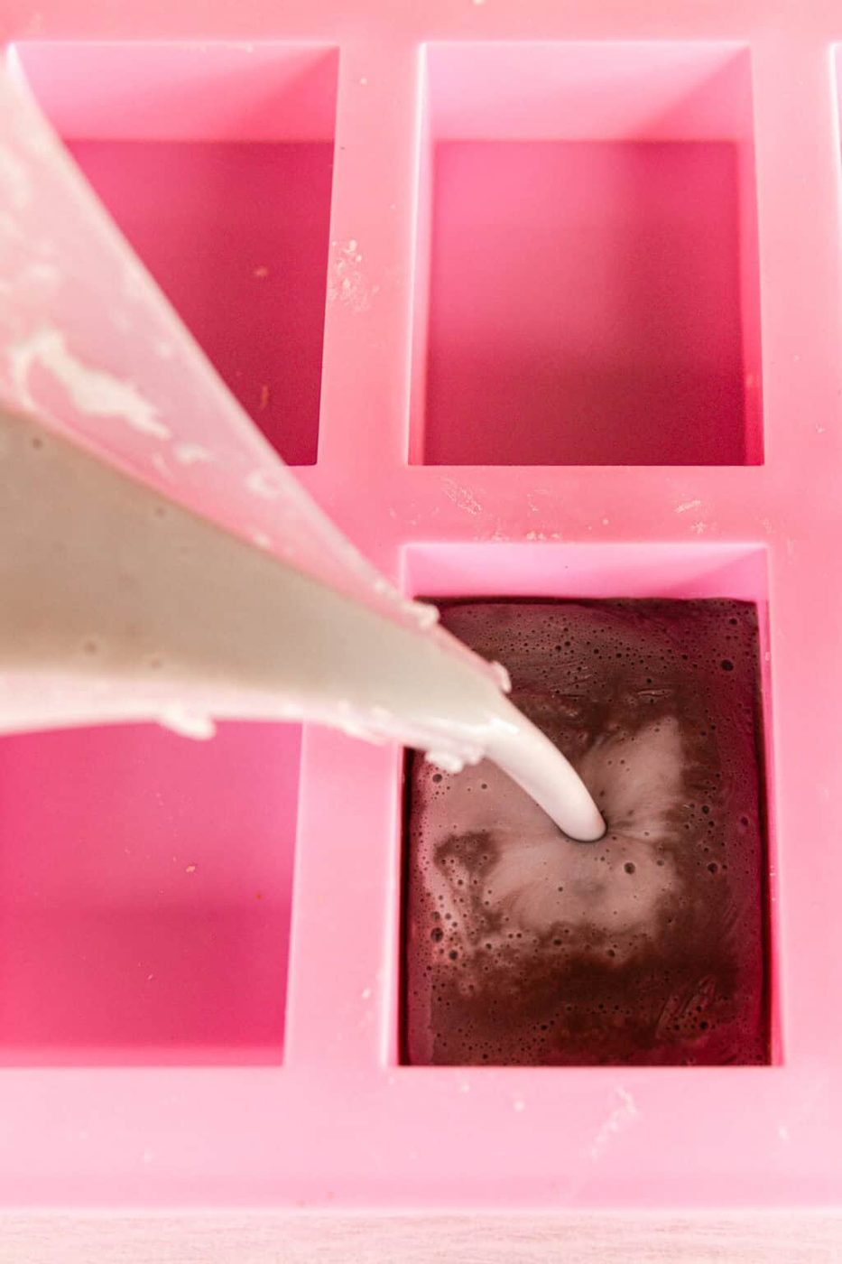 Pouring melted soap base mixture into silicone soap molds.