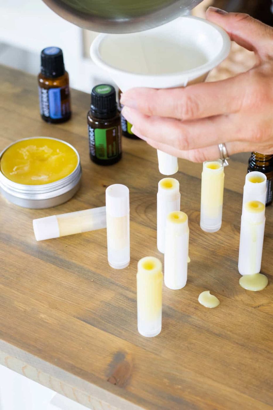 Using a funnel to pour the melted cream into old lip balm tubes.