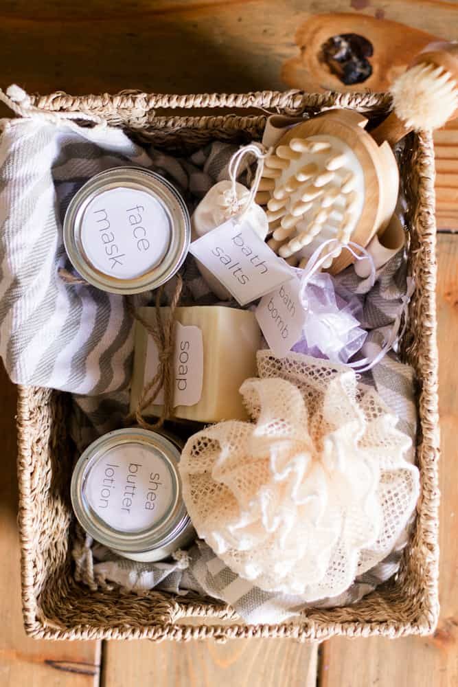 Wicker basket with glass mason jars of bath slats and lotions with white labels.