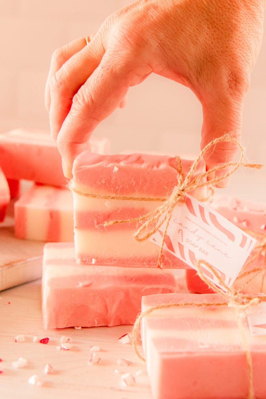 Holding up a bar of candy cane soap tied with twine and a gift tag.
