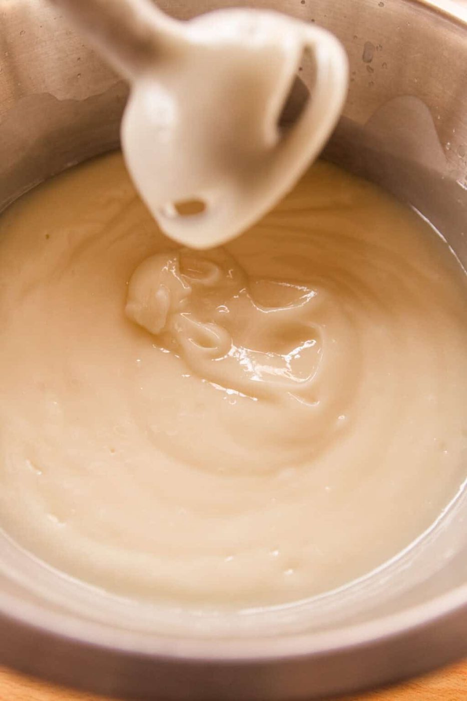 Using an immersion blender to blend the soap mixture together.