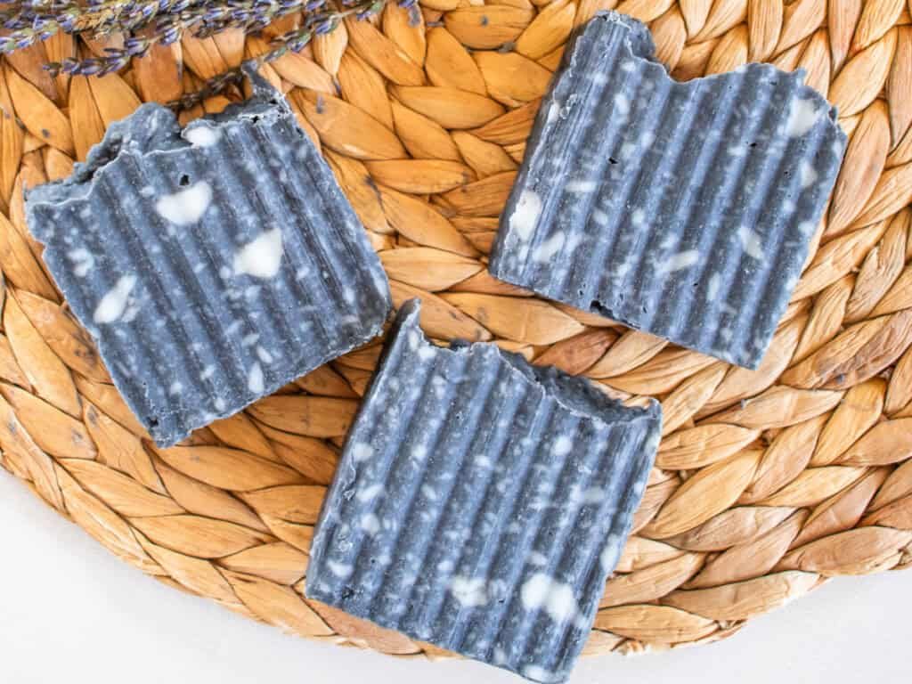 Three bars of charcoal soap on a wicker placemat.