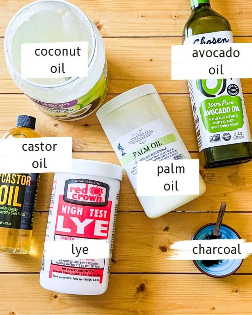 Activated charcoal soap ingredients labeled on a wooden table.