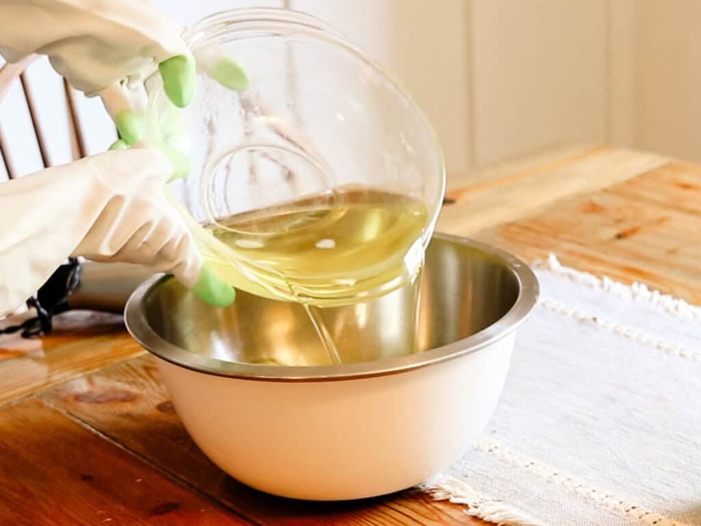 Pouring oils into a metal mixing bowl.