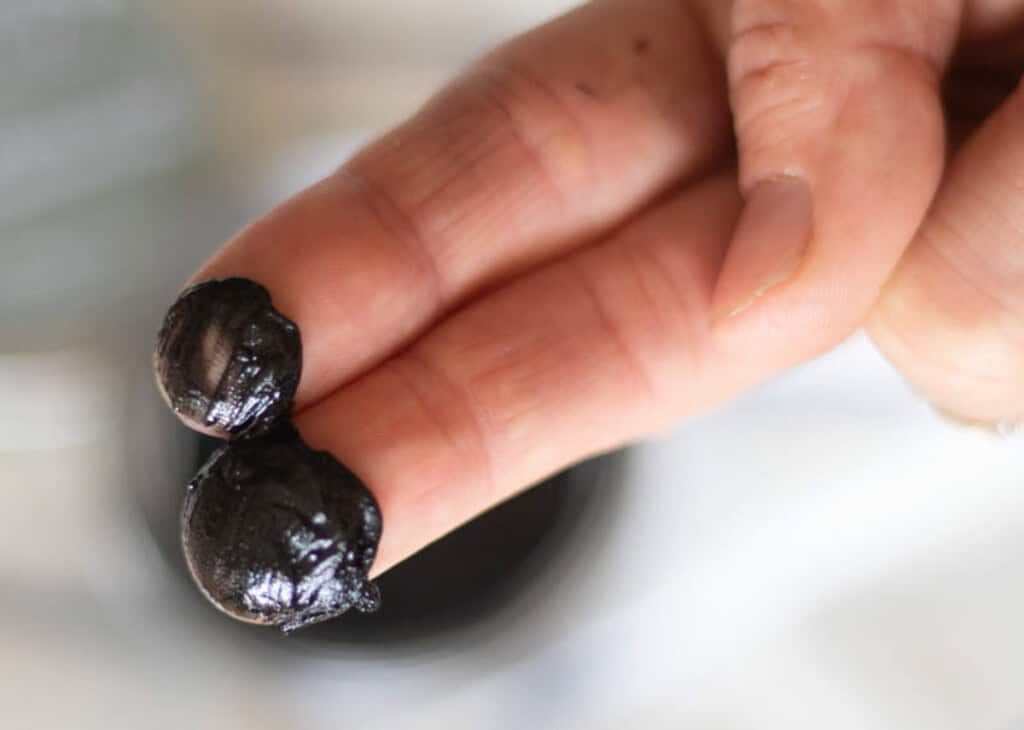Two fingers dipped in black drawing salve.