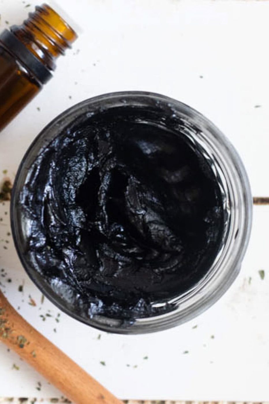 A jar of drawing salve with a bottle of essential oils next to it.