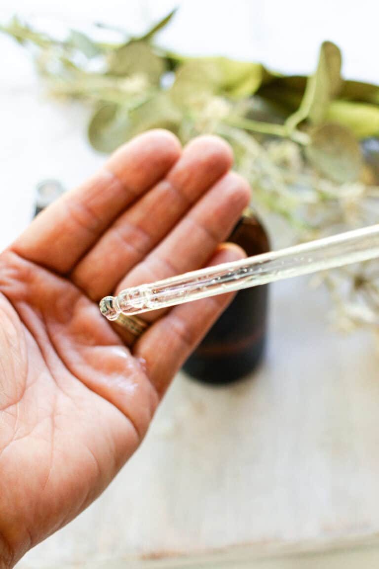 Putting a few drops of DIY facial oil into the palms of our hands.
