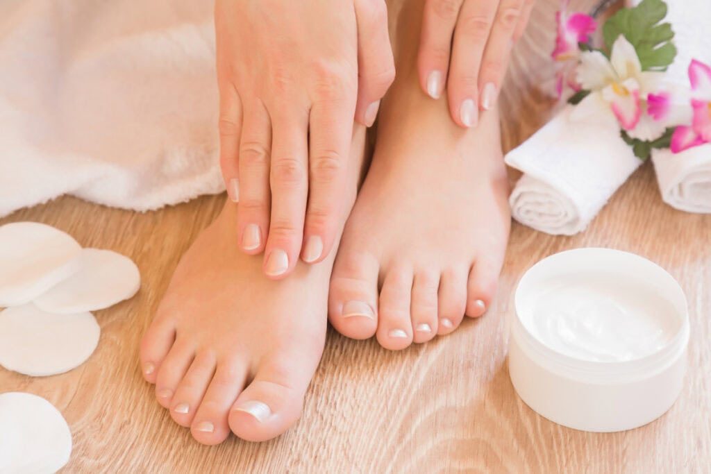 Feet with foot cream next to them.