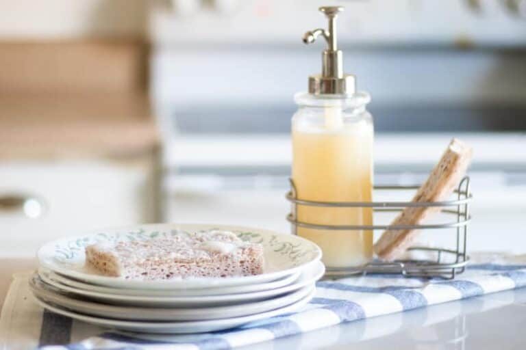 dish soap sponge with DIY dish soap sitting on stack of white plates