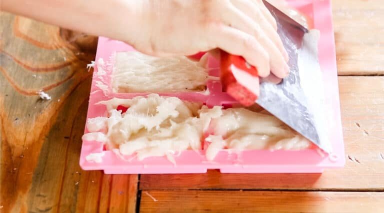 Smoothing the tops of the soap with a metal scraper before they harden.
