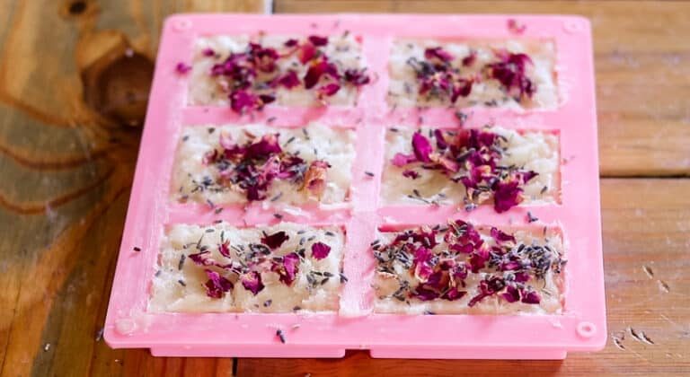 Sprinkling the top of 6 soap bars with dried rose petals.