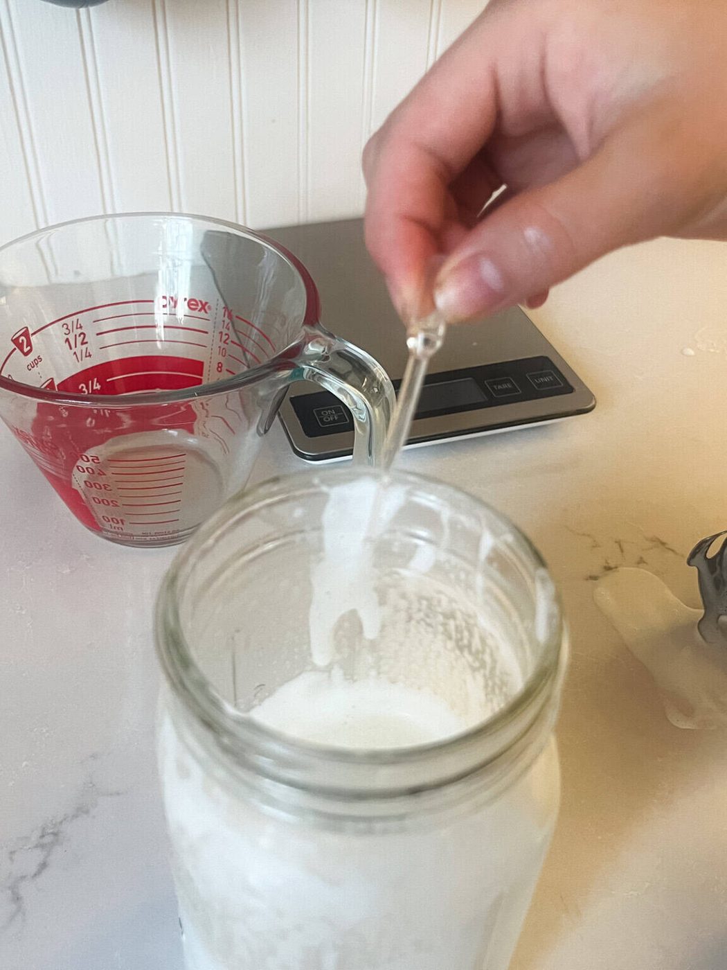 Checking the pH of homemade goats milk lotion in a mason jar.