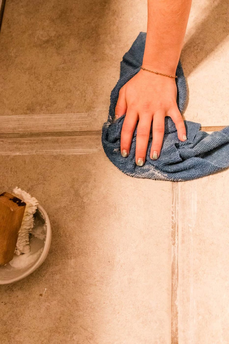 Wiping a grout line with a microfiber cloth.
