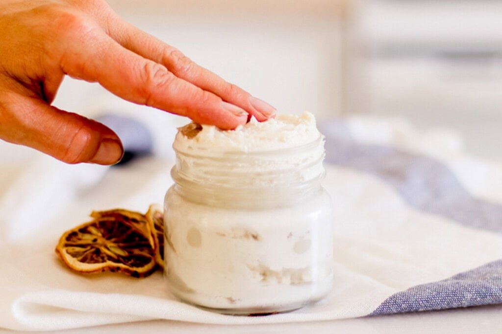 Using fingertips to get a little shea butter lotionout of the airtight container.