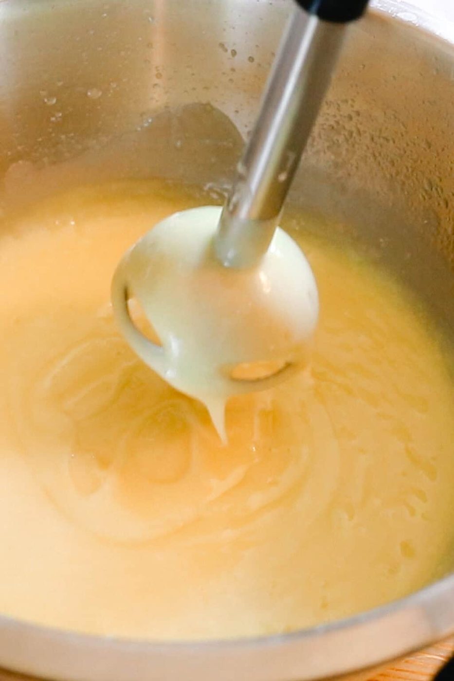 Checking the trace of the soap mixture by holding the immersion blender over it as the soap drips down.