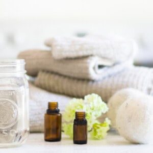 Homemade fabric softener on a laundry folding table with towels and dryer balls next to it.