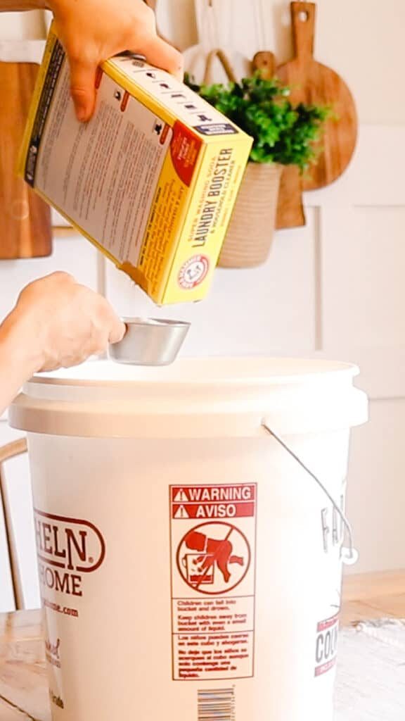 Measuring out washing soda and pouring into the large bucket.