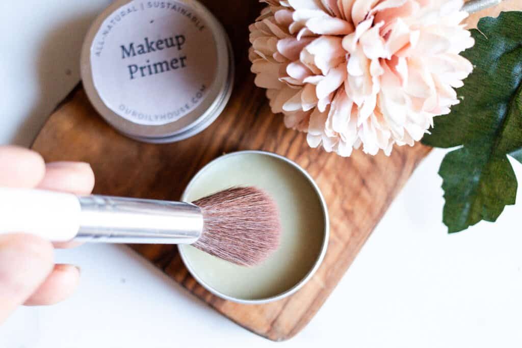 A pot of diy primer with makeup brushes and pretty flowers.