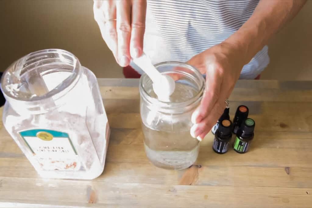 Pouring baking soda into a jar to make homemade mouthwash.