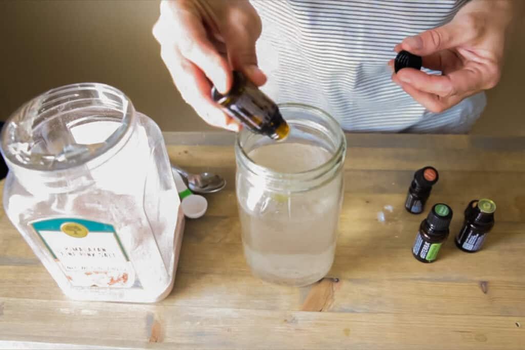 Dropping essential oils into a jar of homemade mouthwash.