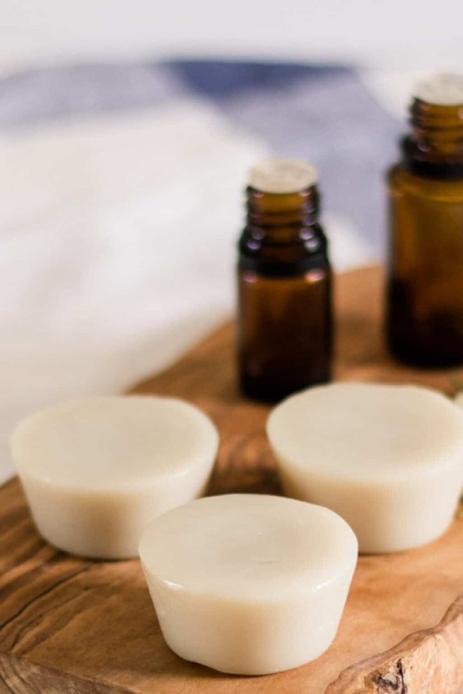 Muscle rub lotion bars on a wooden board with essential oil bottles.