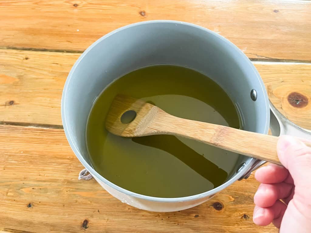 A pot of melted oils with a wooden spoon.
