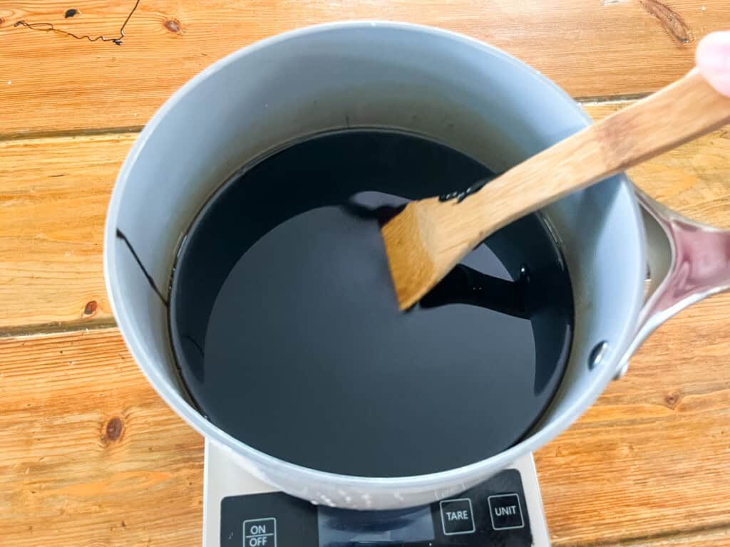 A pot of melted oils and pine tar on a digital scale.