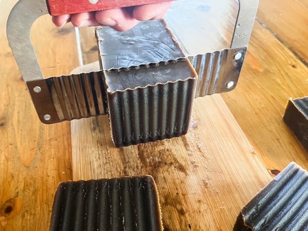 Cutting a block of soap into bars with a crinkle cutter.
