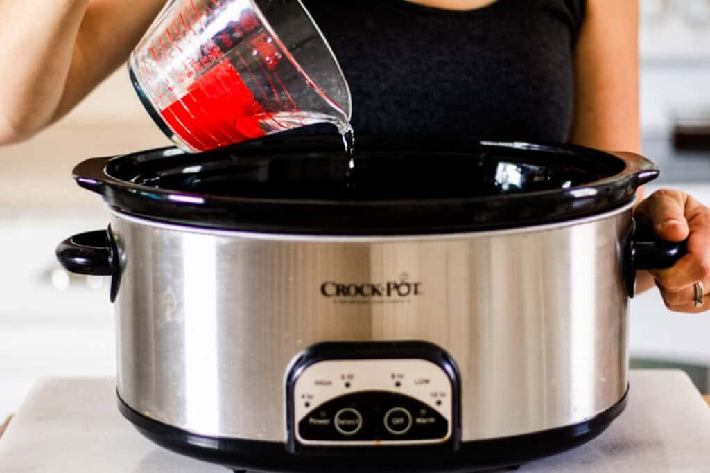 Pouring water into a crockpot.