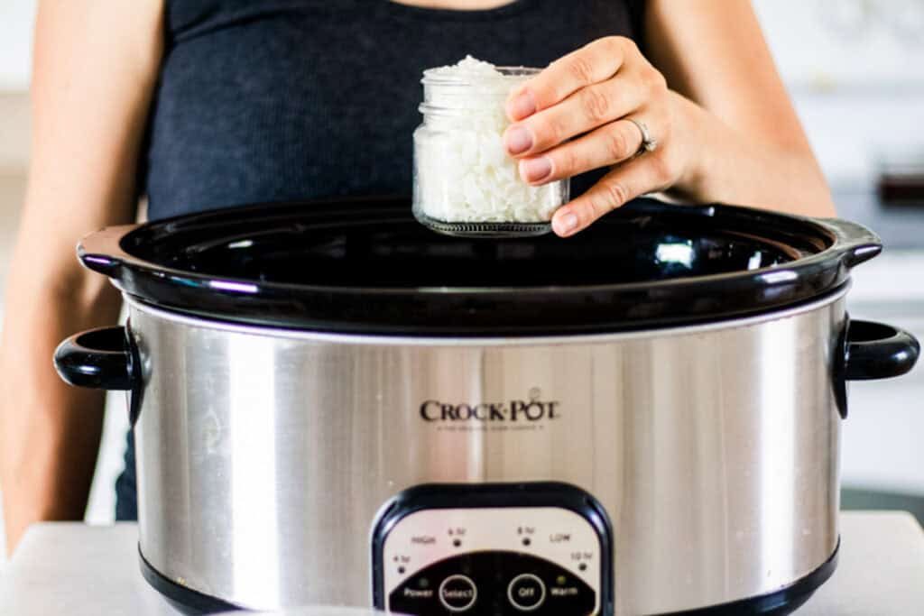 Adding a jar of wax to a crockpot of water.