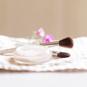 Homemade setting powder in a shallow dish with an applicator brush next to it.
