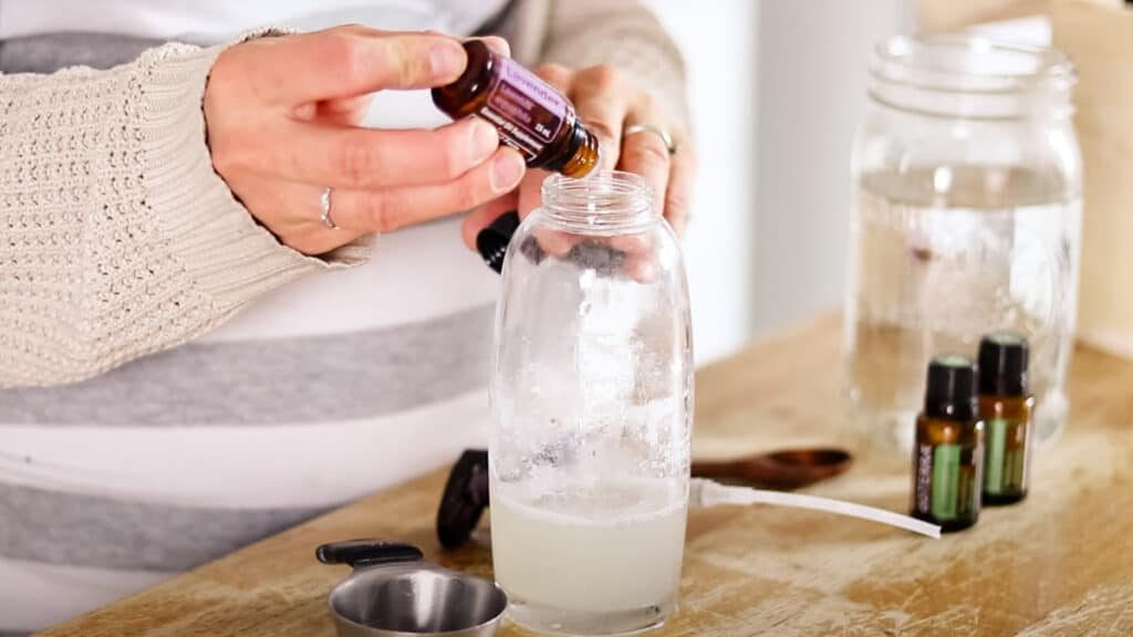 Carefully dropping in the correct number of lavender essential oils into the shampoo.