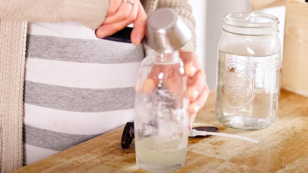 Using a measuring cup to add the liquid ingredients to the shampoo bottle.