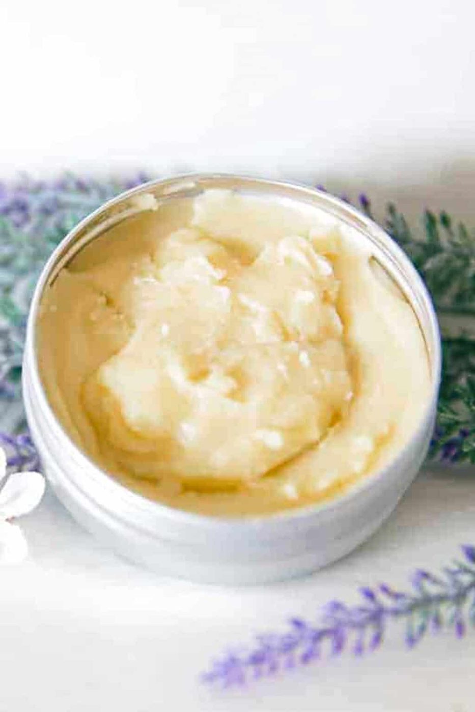A small tin of homemade skin salve on a white vanity.