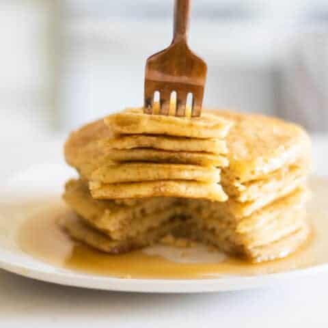 Sourdough pancakes with maple syrup in white plate.