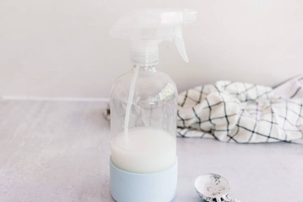 Homemade starch spray on a white marble laundry table.
