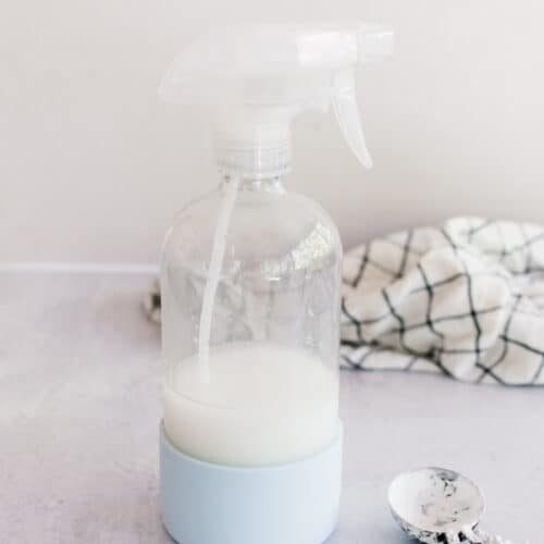 Homemade starch spray on a white marble laundry table.