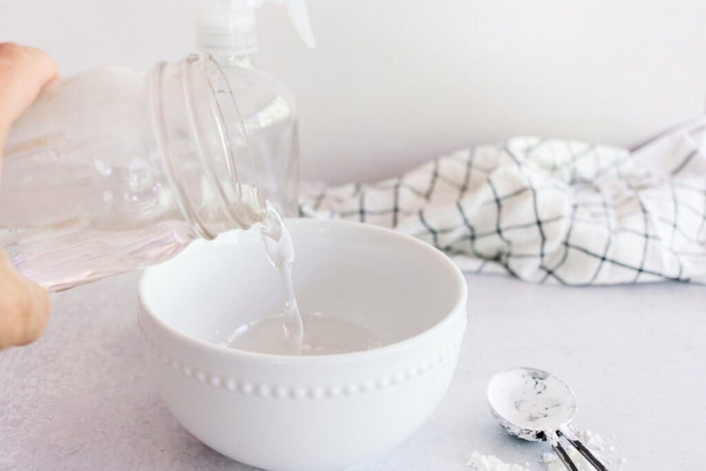 Pouring water into a bowl to make homemade spray starch.