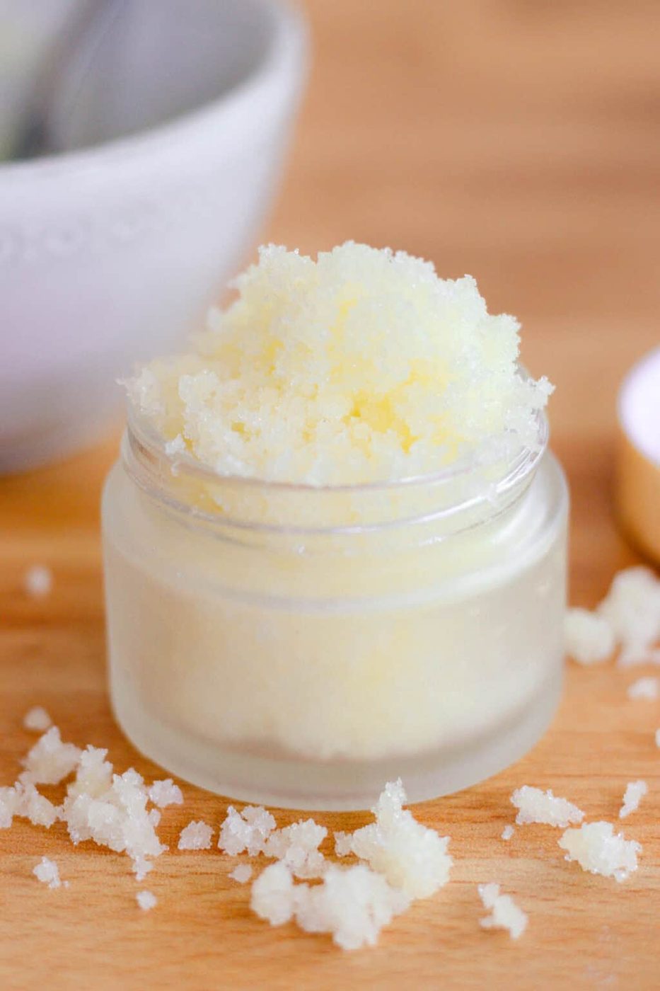 Homemade sugar scrub in glass jar on wooden table.
