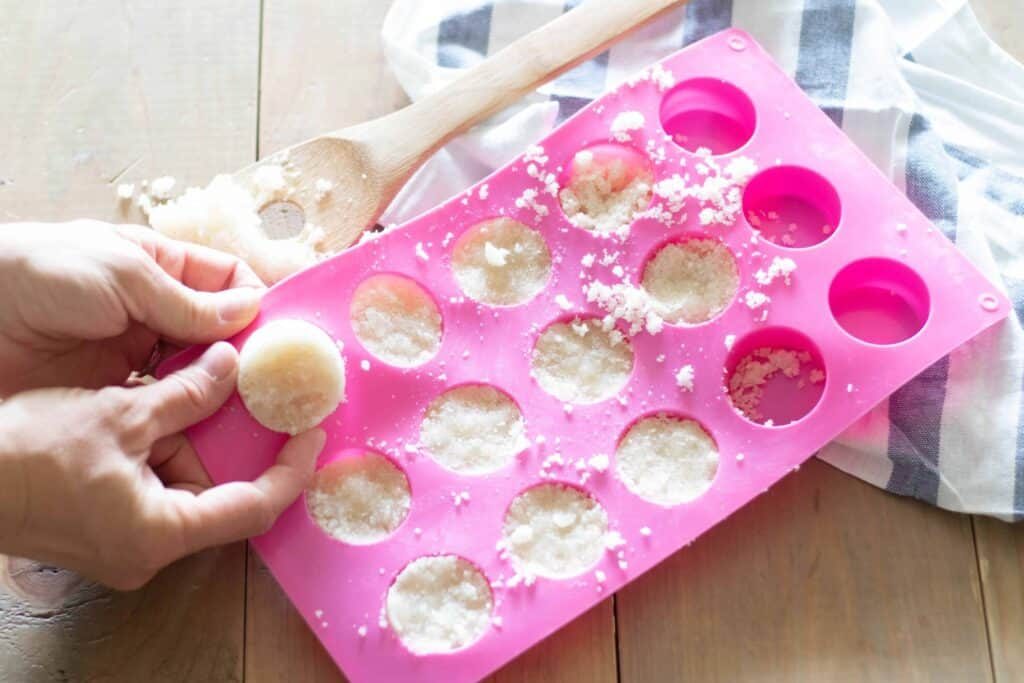 Mini sugar scrub bars in pink silicone molds on wooden table.