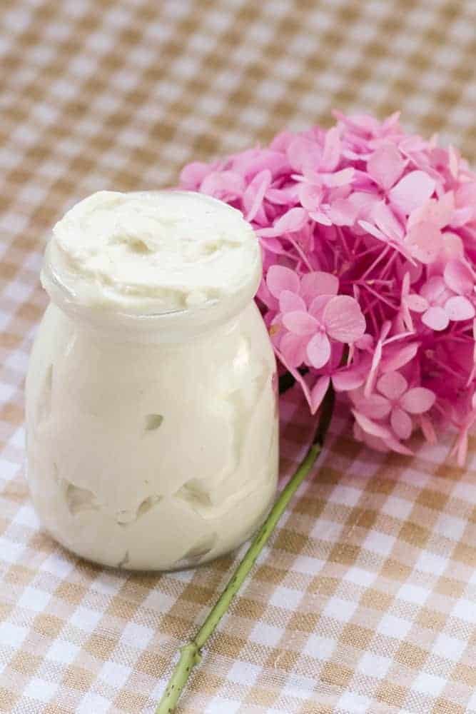 A jar of tallow body butter with pink flowers.