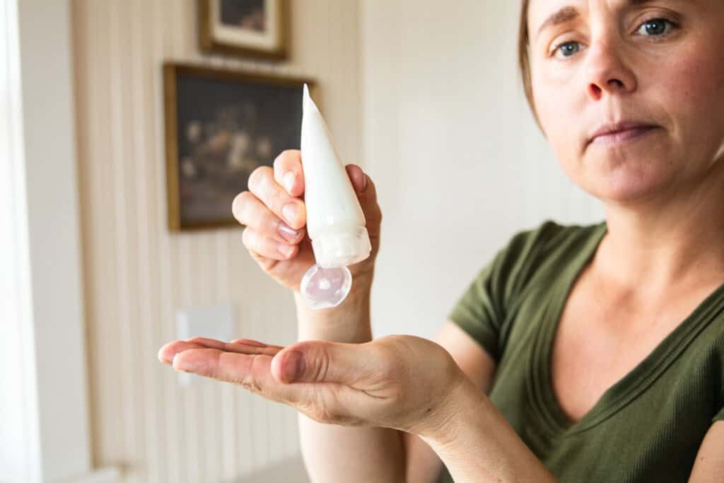 Squeezing homemade tallow lotion from a tube into the palm.