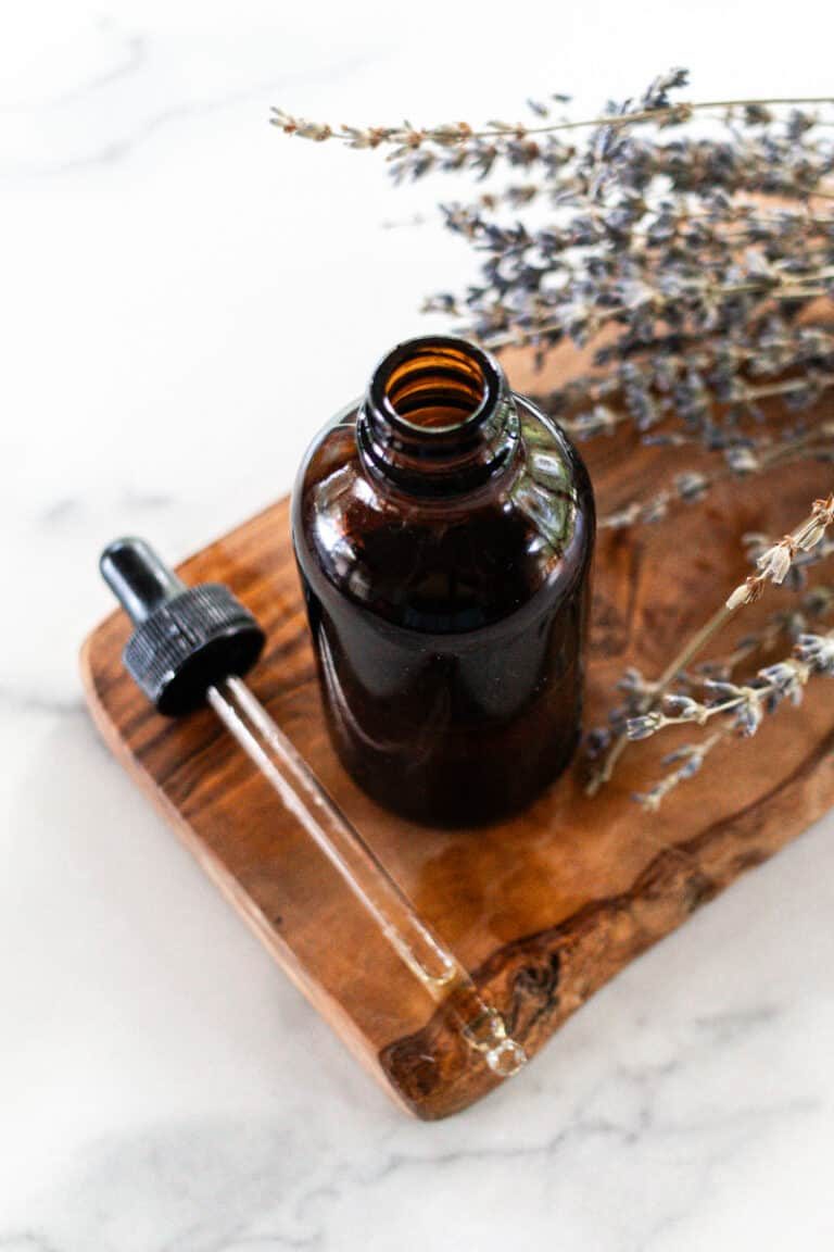 Tanning oil in a glass dropper bottle on a white marble.