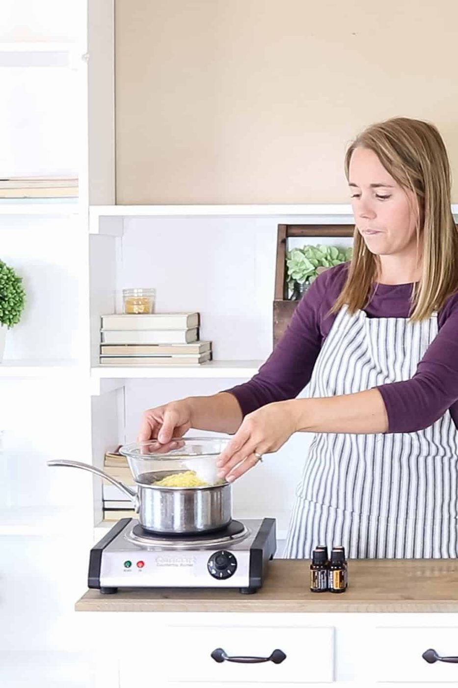 the studio placing a bowl of wax on top of a boiling pot of water to create a double boiler.