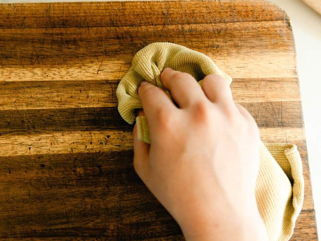 Rubbing wood balm into a wooden cutting board with a soft cloth.